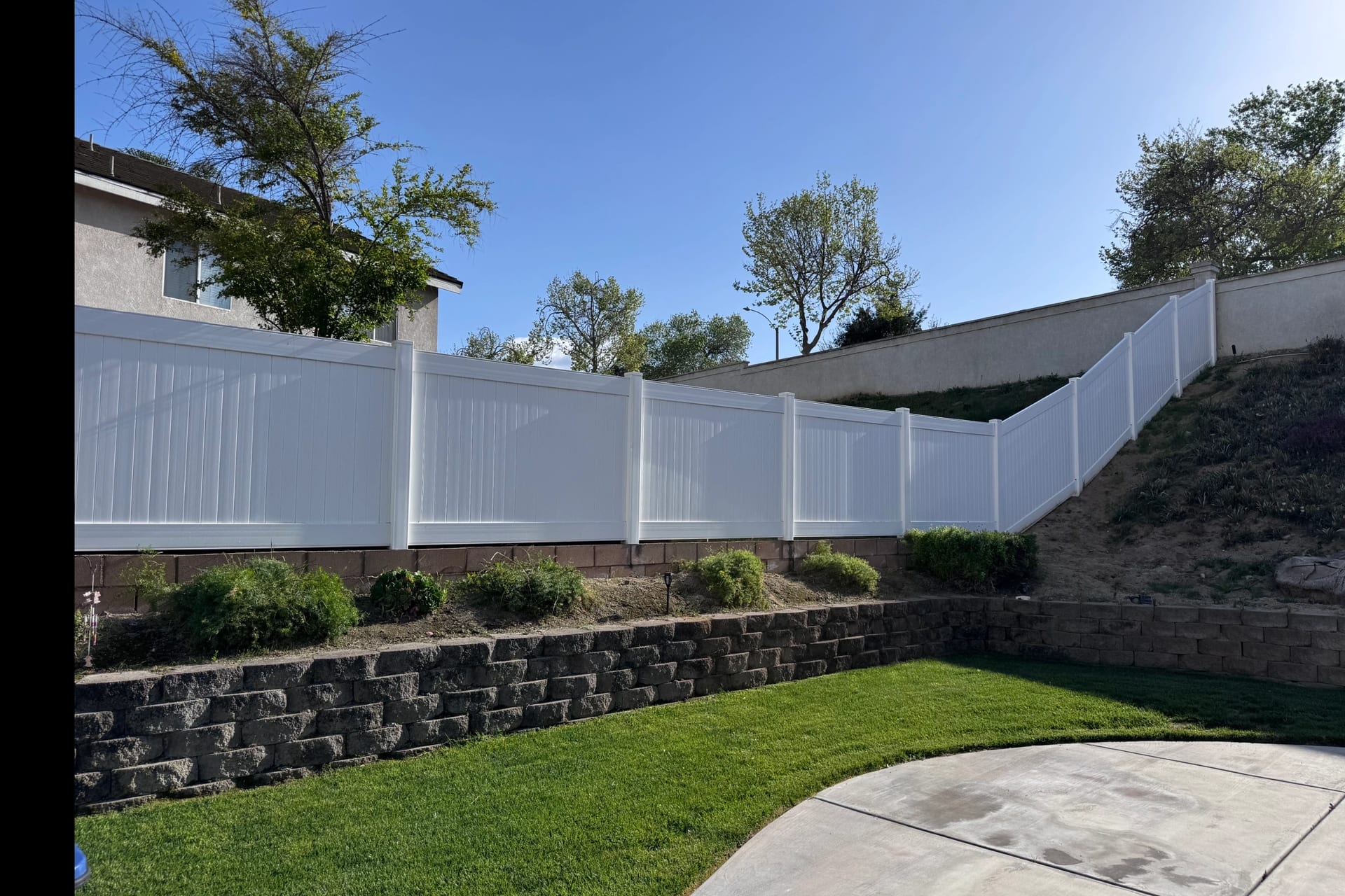 White vinyl privacy fence installed by Banda's Fence on a hillside lot in Phelan, California